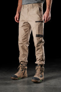 A pair of khaki FXD WP-4 Men's Cuffed Stretch Work Pants paired with brown boots.