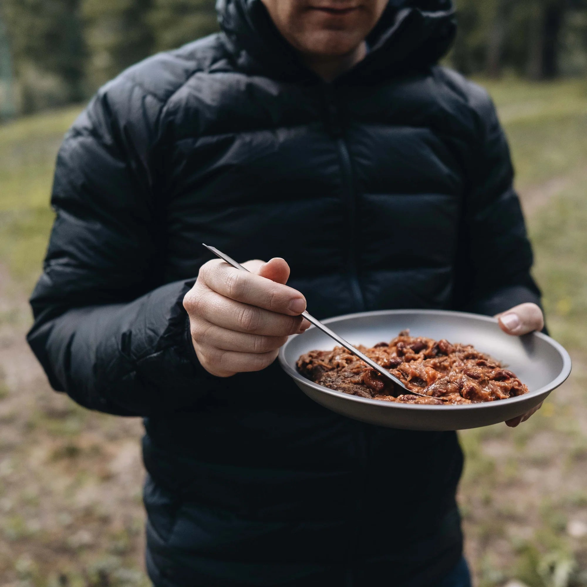 Man eating stew out of Alton Goods Ultralight Titanium Plate