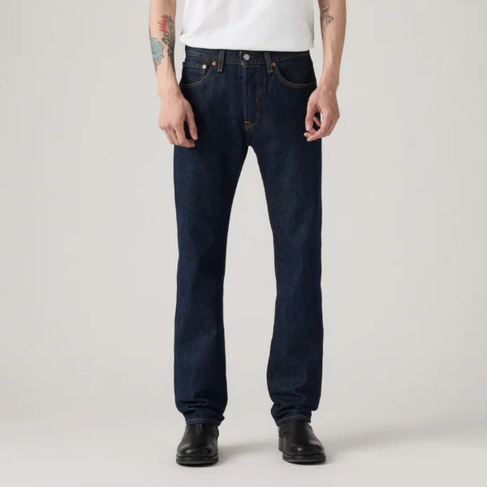 Person wearing dark blue Levi 501 jeans on a plain background