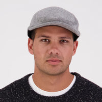 A person wearing a grey Swanndri Bristol flat cap.