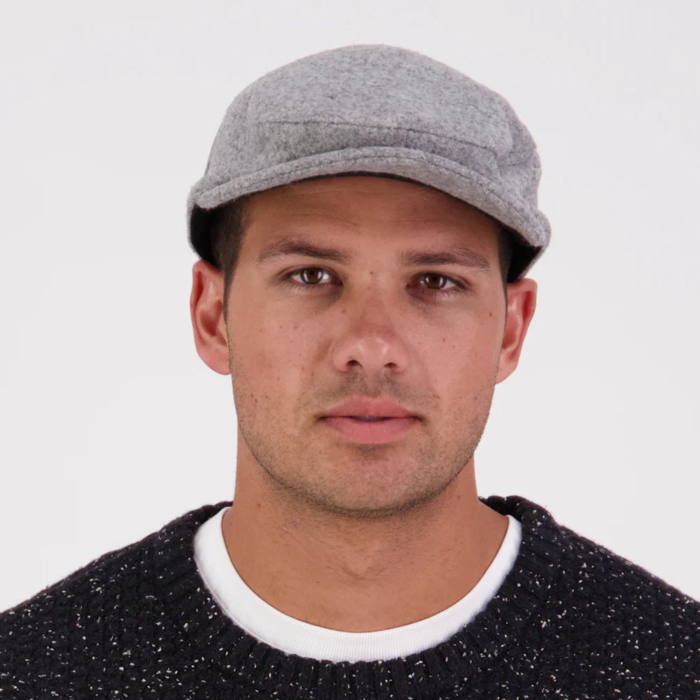 A person wearing a grey Swanndri Bristol flat cap.