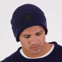 Man wearing a navy blue textured Swanndri beanie with a brand patch on the front.