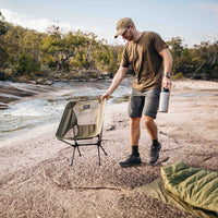 Man placing Alton Goods Ultralight Camp Chair next to stream