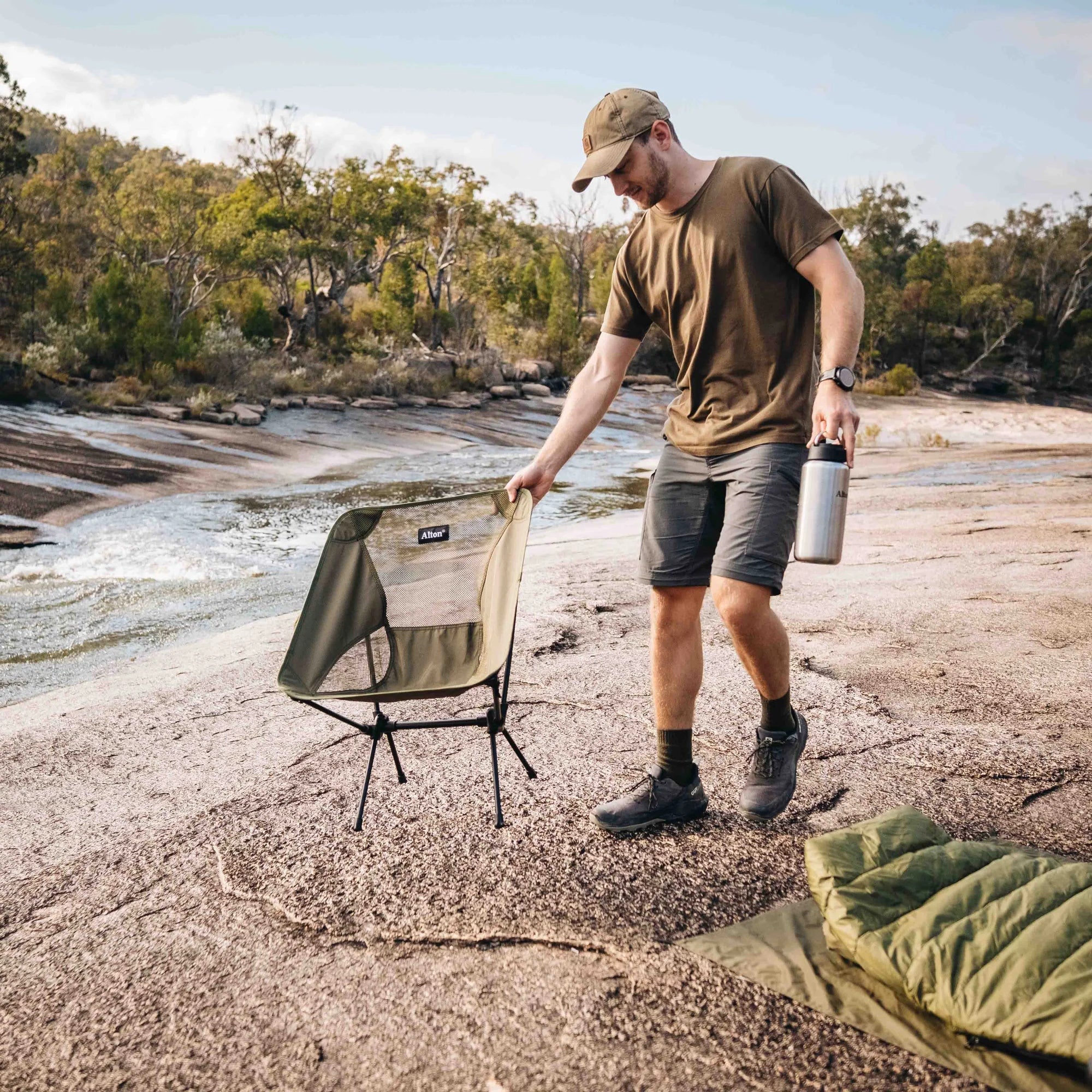 Man placing Alton Goods Ultralight Camp Chair next to stream