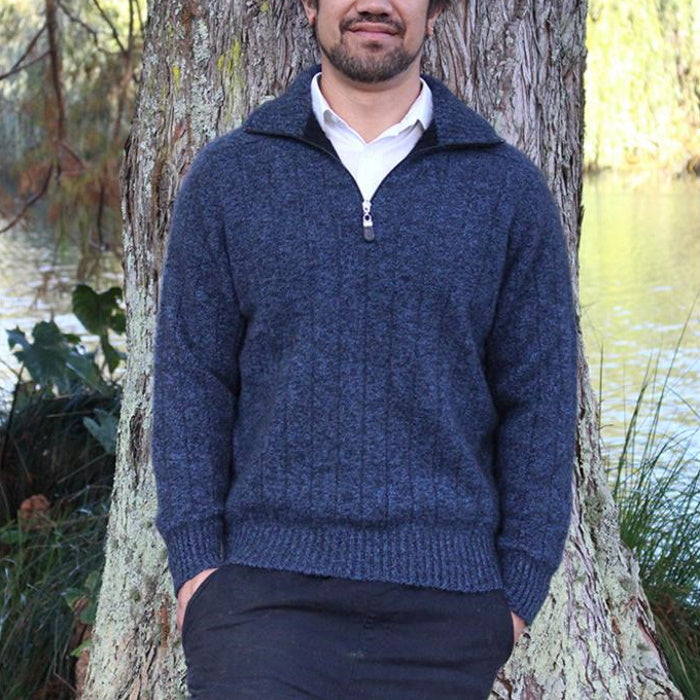 Male model standing against a tree wearing a Lothlorian zip collar rib jumper in Blue Marle, with Blue jeans.