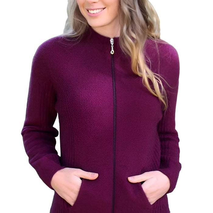Female model wearing Lothlorian full zip possum merino jacket in Berry. The model has her hands in both pockets and the background is a riverbank.