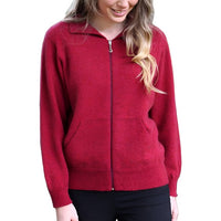 Female model wearing a raspberry red Lothlorian plain zip cardigan against a river background.