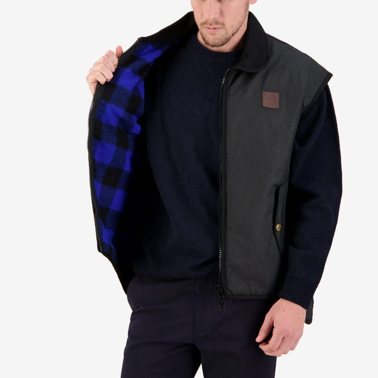 Model opening Swanndri Foxton Oilskin Vest in Black to show Blue & Black check lining.