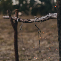 Close up of Alton Goods Ultralight Grill Hangers hooks attached to stick