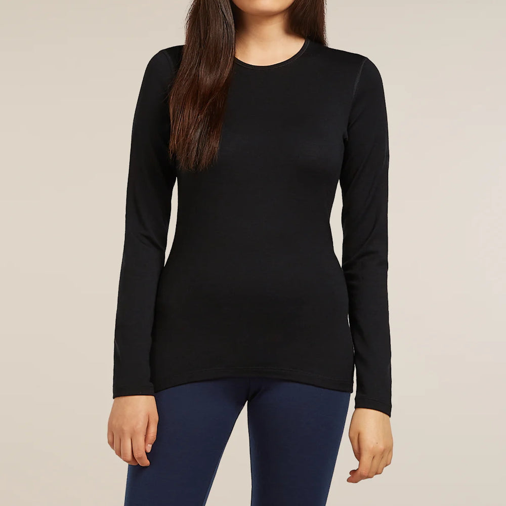 A woman wearing a black Icebreaker long-sleeve crew neck top and navy blue leggings