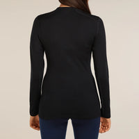 A woman viewed from the back wearing a fitted black long sleeve Icebreaker top and dark blue leggings