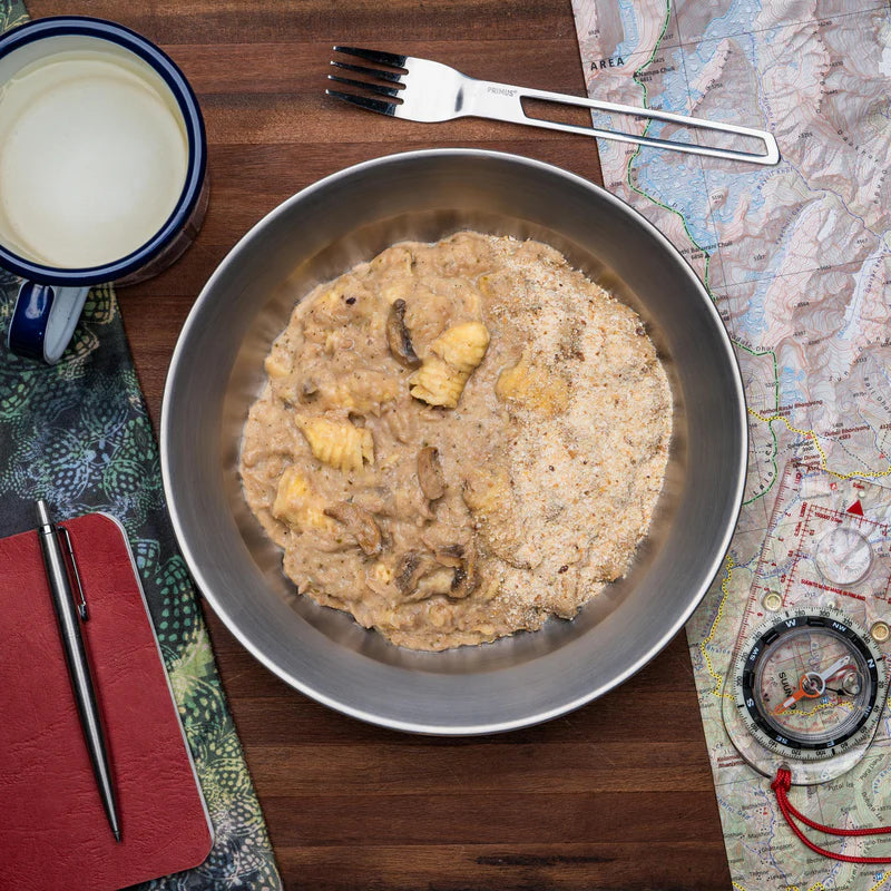 Bowl of tuna pasta bake on table with map, compass and fork