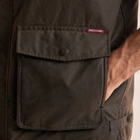 Close-up of a dark brown oilskin vest with a visible Driza-Bone brand label.