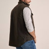 Back of man wearing a Driza-Bone brown vest over a grey shirt and blue jeans.