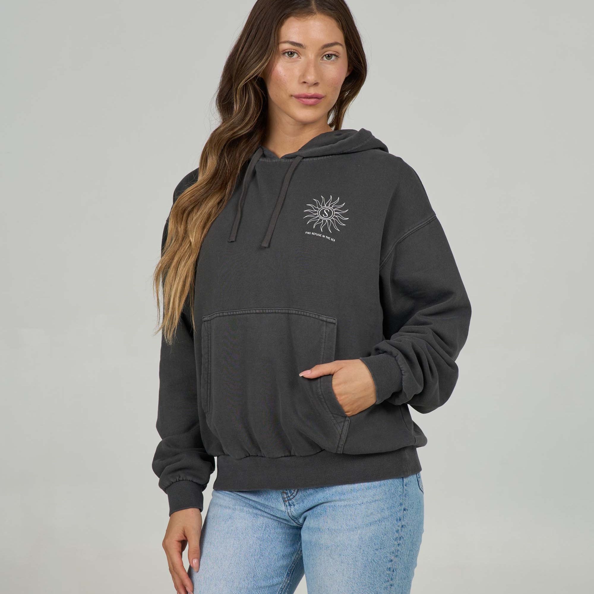 Woman wearing a faded black hoodie with a Salty Crew logo
