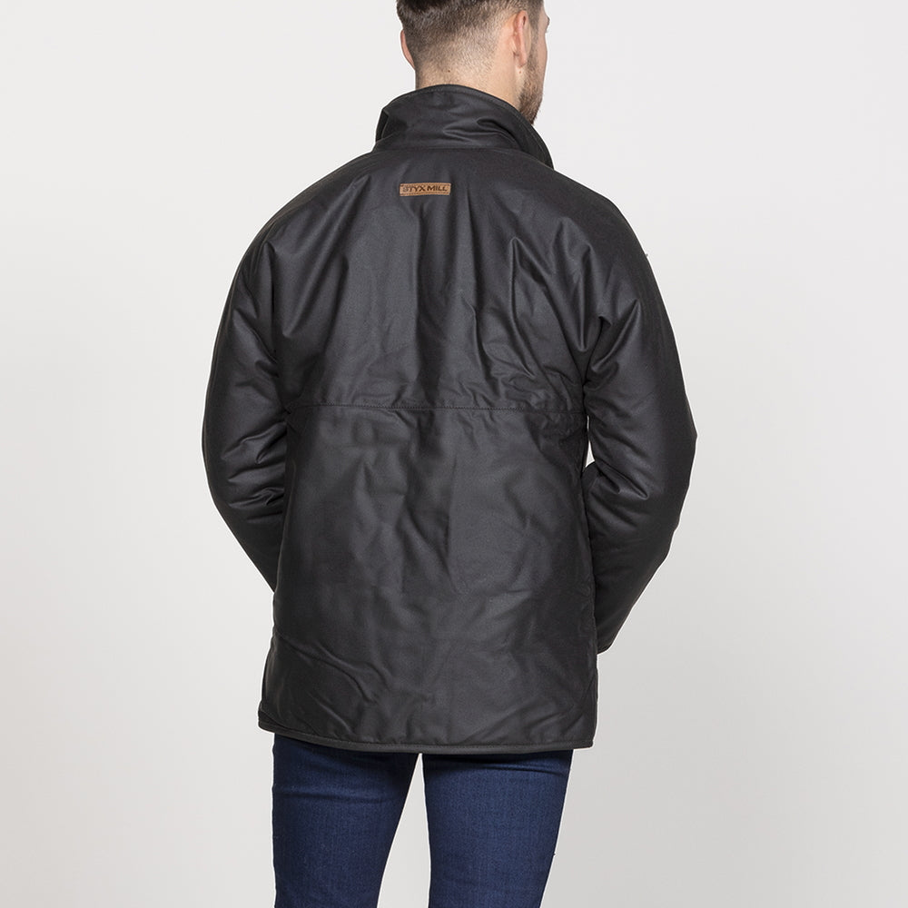 A man viewed from the back wearing a brown waxed cotton jacket