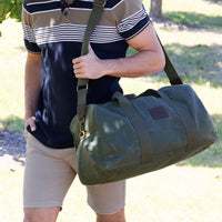 Person holding a green Thomas Cook duffel bag outdoors
