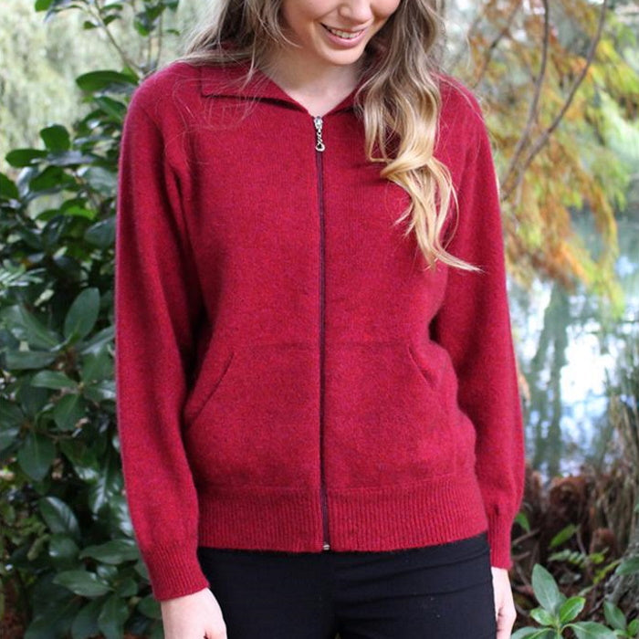 Female model wearing a raspberry red Lothlorian plain zip cardigan against a river background.